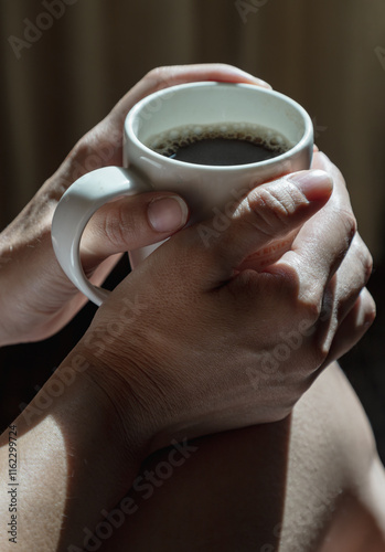 Obraz na płótnie Close-up of Comforting cozy female hands holding a coffee mug with the morning sunlight that shines through. Dark tone, use it as your Wallpaper, Poster and Copy space, Selective focus. w salonie