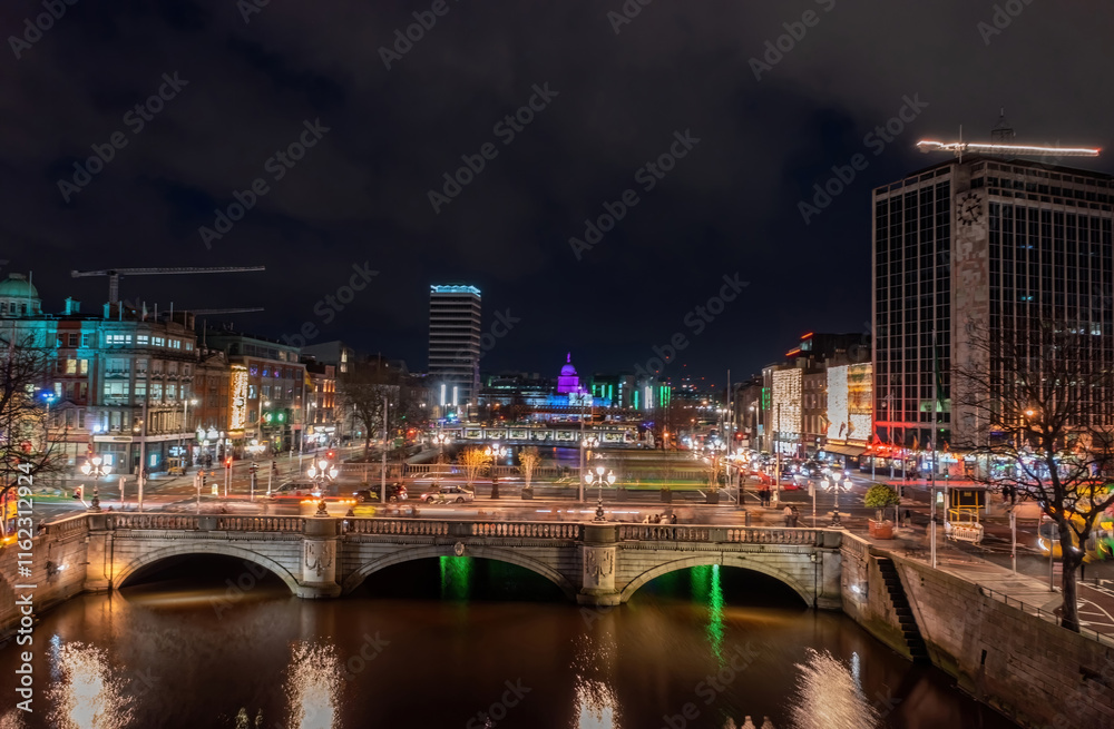 Dublin city centre at night during the Christmas holidays, featuring bustling activity and motion blur trails from passing traffic and pedestrians Dublin city centre at night during the Christmas holidays, featuring bustling activity and motion blur trails from passing traffic and pedestrians