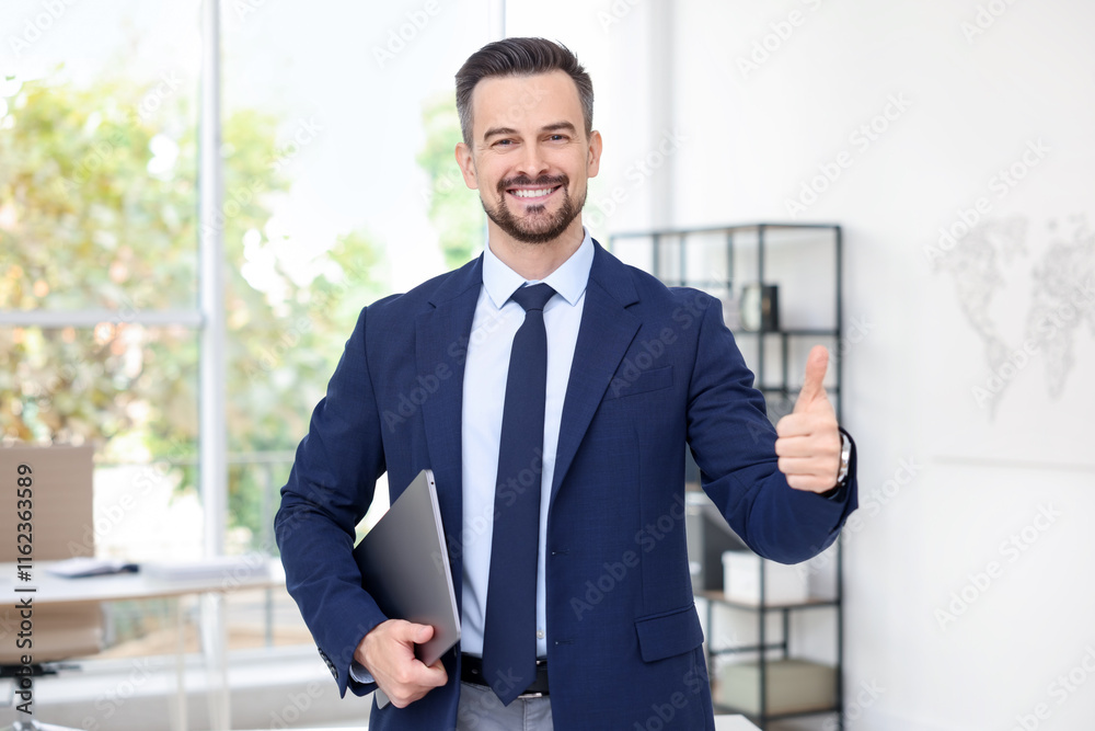Portrait of smiling banker with laptop showing thumbs up in office Portrait of smiling banker with laptop showing thumbs up in office