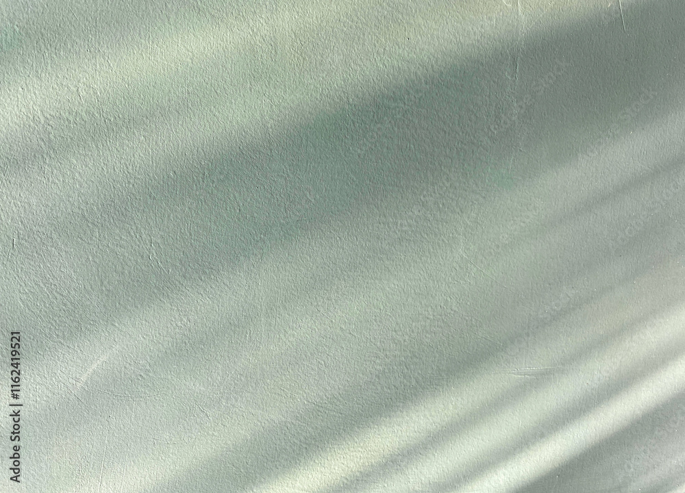 Obraz premium Abstract Shadows on Green Surface. A minimalist capture of soft light shadows cast on a textured green surface
