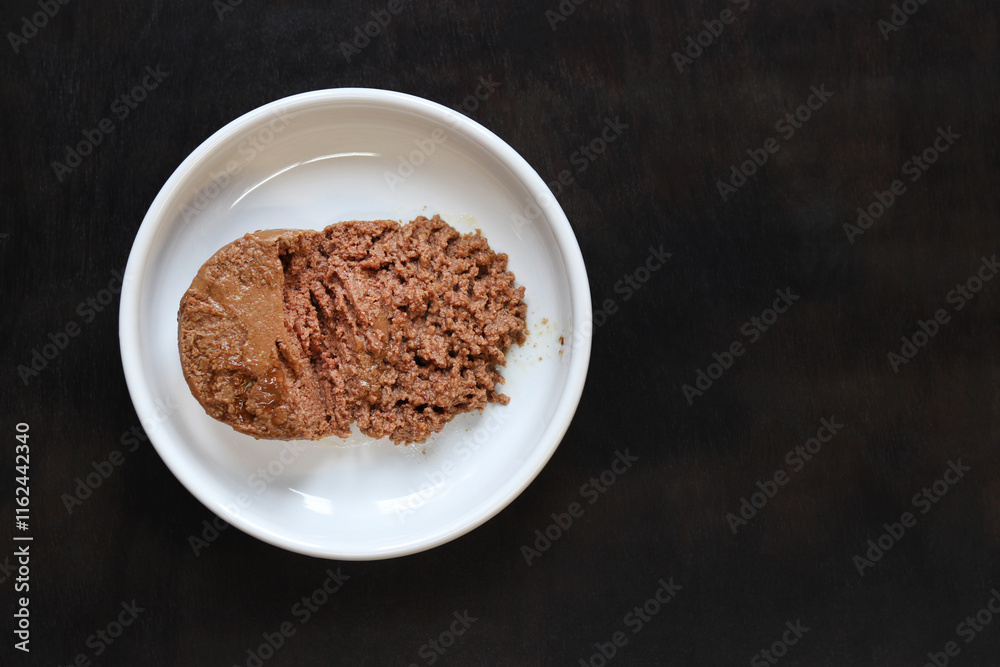 Cat food, pate, top view. Canned food for pets in a round white plate on a dark background. Tasty and healthy food for domestic cats. A portion of wet food, soft pate for a cat on a plate. Copy space Cat food, pate, top view. Canned food for pets in a round white plate on a dark background. Tasty and healthy food for domestic cats. A portion of wet food, soft pate for a cat on a plate. Copy space