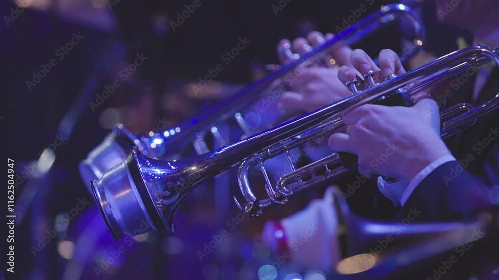 The trumpet section of a big band playing their instruments using cup mutes during a live concert performance in dim stage lights
