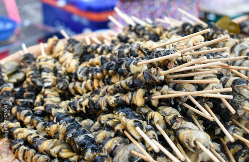 Skewered clams are grilled on a grill for food.
