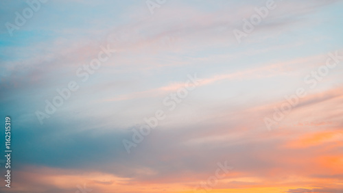 Fototapeta Naklejka Na Ścianę i Meble -  Dynamic sunset scene showcasing streaks of orange and pink clouds against a fading blue sky.