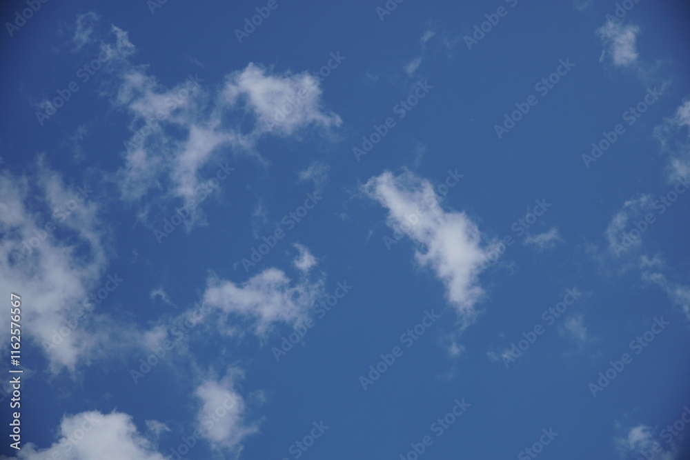 Clear blue sky with a few clouds. The sky is very bright and the clouds are scattered throughout Clear blue sky with a few clouds. The sky is very bright and the clouds are scattered throughout