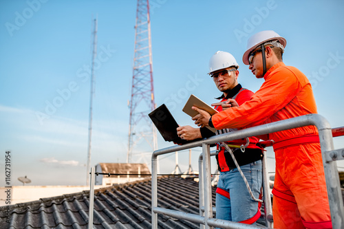 Two engineers are planning to install solar cells on the roof of a building. photo