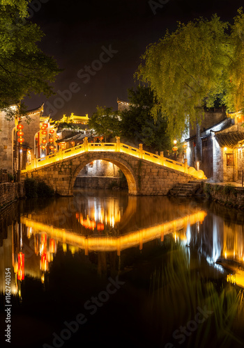 Scenic night view of illuminated bridge and reflection in ancient water town