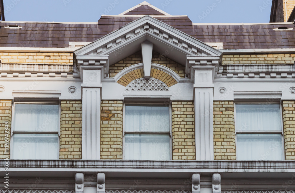 Classical architectural details of a neoclassical building facade with white columns and ornate pediment against light yellow brickwork Classical architectural details of a neoclassical building facade with white columns and ornate pediment against light yellow brickwork