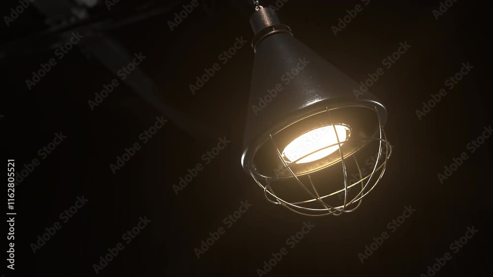 Old industrial lamp swinging from the ceiling. Loopable animation of an old lamp moving left and right. Close up.