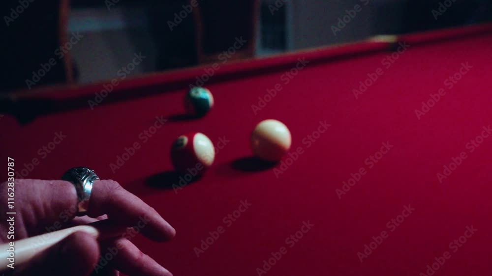 Closeup of a player hitting Poll balls game on a red table with a blurred player in the background