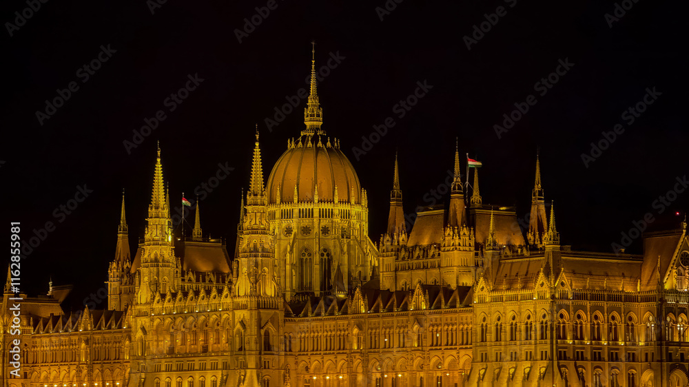 Fototapeta premium Illuminated at night, the Hungarian Parliament Building in Budapest represents architectural grandeur, making it ideal for European travel themes