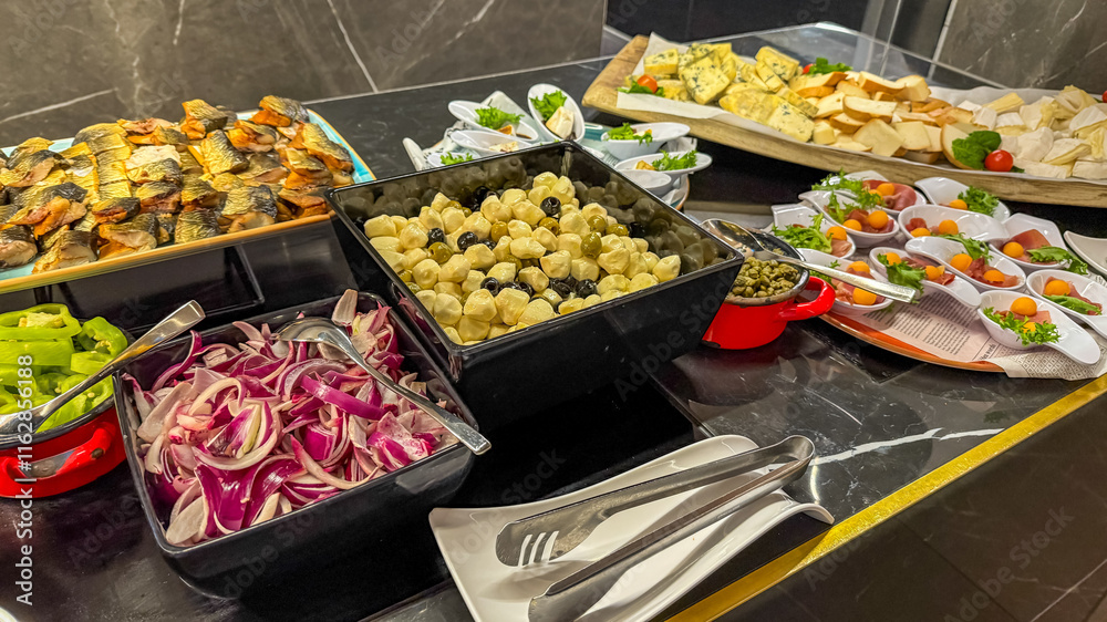 Fototapeta premium A gourmet buffet spread featuring assorted cheeses, marinated vegetables, and smoked fish, ideal for catering events or festive gatherings