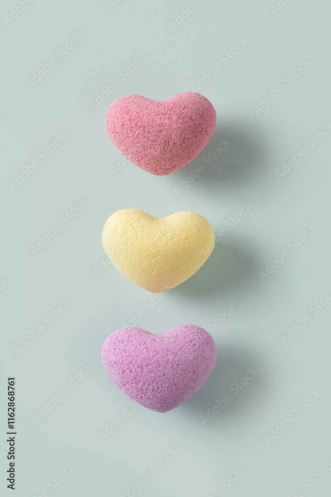 Fototapeta premium Valentine's Day three heart shaped bath salt on pastel blue background. View from above. Love creative spa concept.
