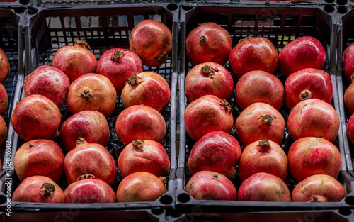 Photography A vibrant display of fresh pomegranates neatly organized in black market crates