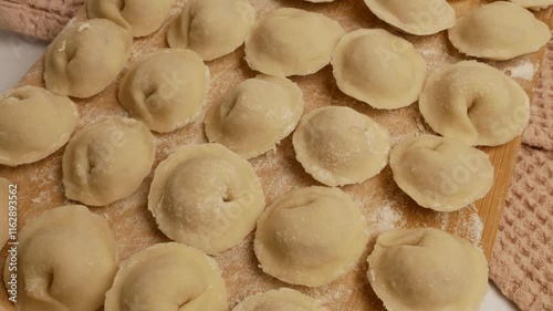 Handmade dumplings are lined up on a board, waiting to be steamed or fried.