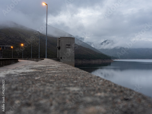 View of the Vilarinho das Furnas dam, with the reservoir water reflecting the surrounding landscape, at dusk. Campo do Gerês, Portugal.
