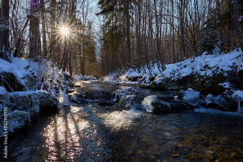 Landschaftsfoto. Winterlicher Bach mit Sonnenstern am Himmel. Bei kalten Temperaturen. photo