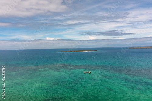 Turquoise sea water with coral reefs and tourist boat. Tropical island under the blue sky and clouds. Bantayan, Cebu. Philippines. photo