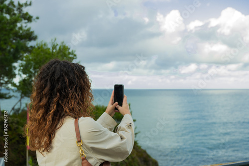 Tourist taking pictures of the cantabrian sea in santander, spain