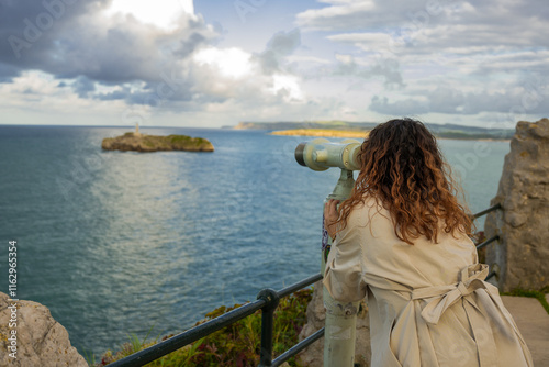 Tourist using binoculars looking at mouro island from magdalena peninsula in santander, spain