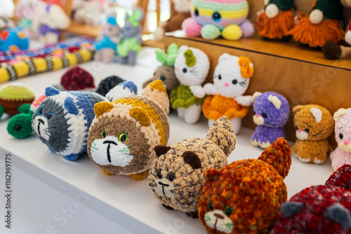 Colorful crocheted and knitted funny cats as souvenirs and gifts on the countertop.