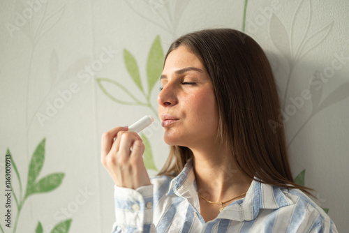 The girl in shirt puts a lip balm on her lips photo