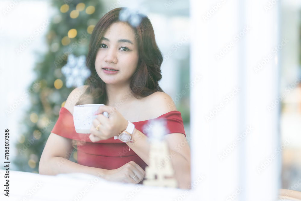 beautiful asian woman relaxing In a red dress holding of positive the having cup of coffee or chocolate at home in the living room indoors Decoration During Christmas x-mas and New Year holiday.