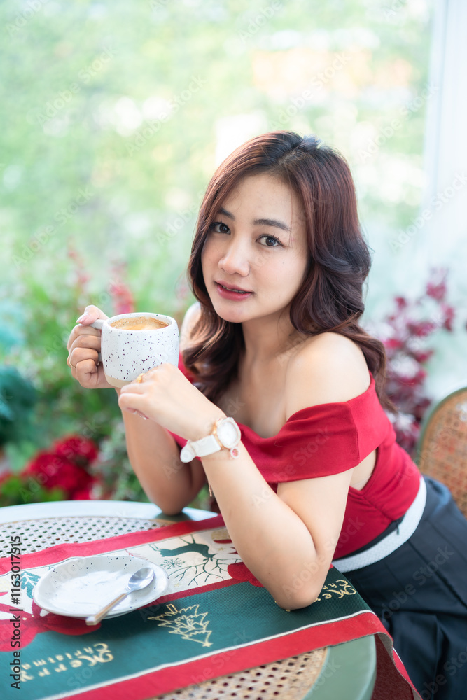 beautiful asian woman relaxing In a red dress holding of positive the having cup of coffee or chocolate at home in the living room indoors Decoration During Christmas x-mas and New Year holiday.