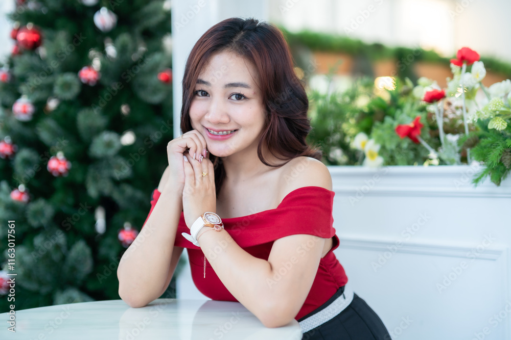 Portrait of beautiful happy Smiling asian woman relaxing In a red dress decorating to a Christmas tree at home in the living room indoors Decoration During Christmas x-mas and New Year holidays.