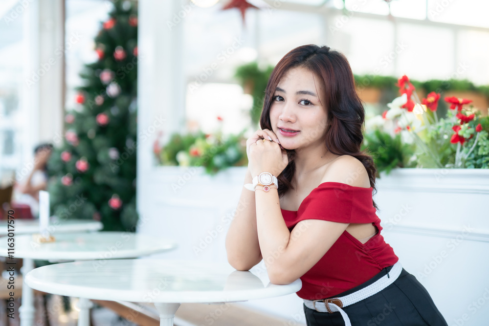 Portrait of beautiful happy Smiling asian woman relaxing In a red dress decorating to a Christmas tree at home in the living room indoors Decoration During Christmas x-mas and New Year holidays.