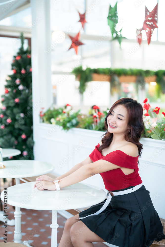Portrait of beautiful happy Smiling asian woman relaxing In a red dress decorating to a Christmas tree at home in the living room indoors Decoration During Christmas x-mas and New Year holidays.