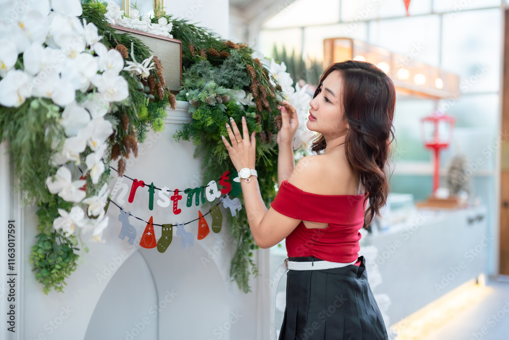 Portrait of beautiful happy Smiling asian woman relaxing In a red dress decorating to a Christmas tree at home in the living room indoors Decoration During Christmas x-mas and New Year holidays.