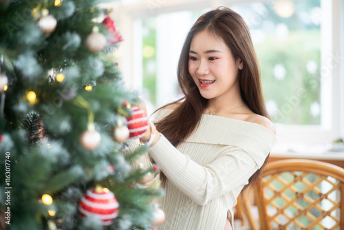 Obraz na płótnie Portrait of beautiful happy Smiling asian woman relaxing sitting decorating to a Christmas tree at home in the living room indoors Decoration During Christmas x-mas and New Year holidays. w salonie
