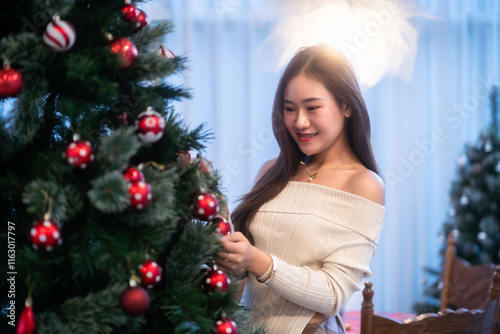 Obraz na płótnie Portrait of beautiful happy Smiling asian woman relaxing sitting decorating to a Christmas tree at home in the living room indoors Decoration During Christmas x-mas and New Year holidays. w salonie