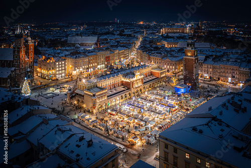 Christmas market with illuminated stalls with snow at night on the Main Market Square in Krakow, Poland (visible Wawel Castle, Cloth Hall - Sukiennice, Town Hall and Mariacki Church) photo