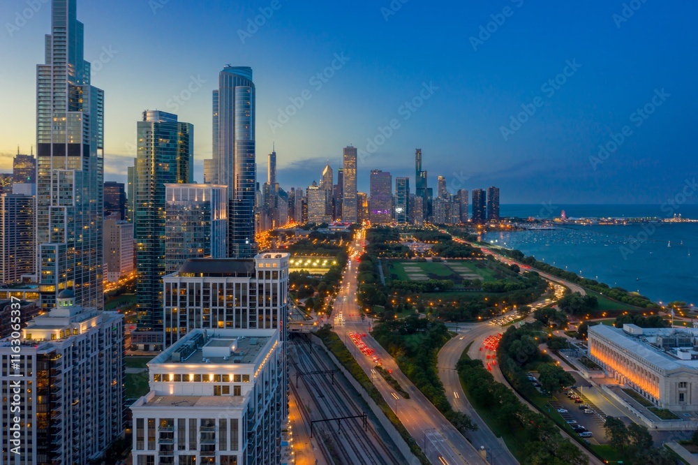 Fototapeta premium Chicago skyline at twilight, illuminated skyscrapers, traffic on Lake Shore Drive, and city park. Urban landscape. Downtown, Chicago, Illinois, United States