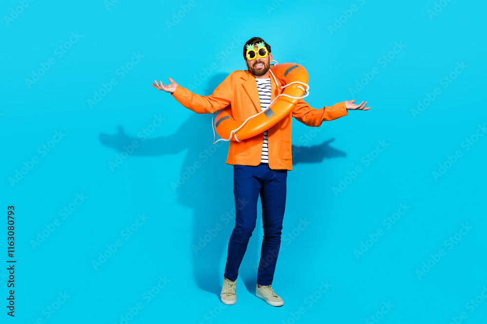 Fototapeta premium Charming young man in vibrant attire with a lifebuoy posing playfully against a turquoise background.