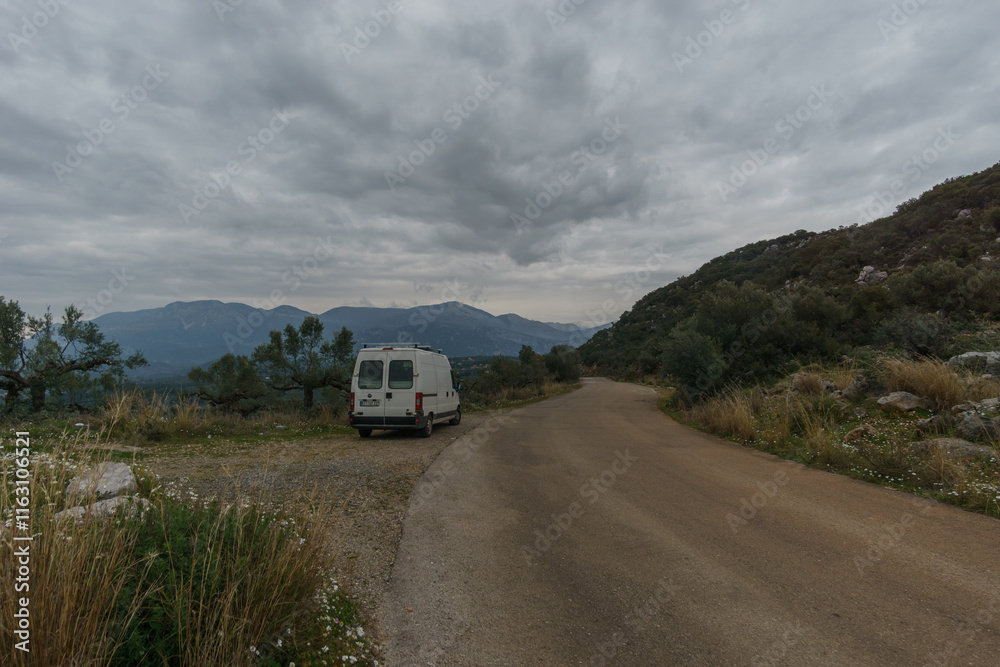 Fototapeta premium Camper Van on a road trip besides small country road in the rural greek scenery, Stavropegial, Messinia, Peloponnese, Greece