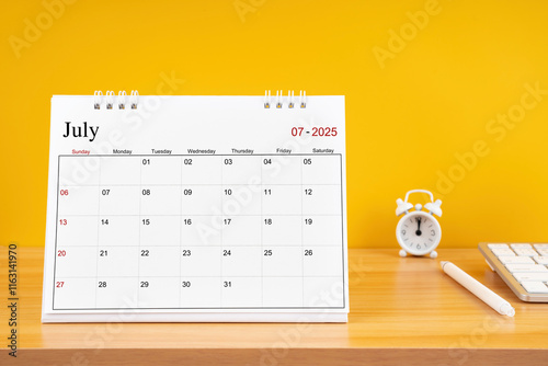 July 2025, Monthly desk calendar for 2025 year on wooden table. photo
