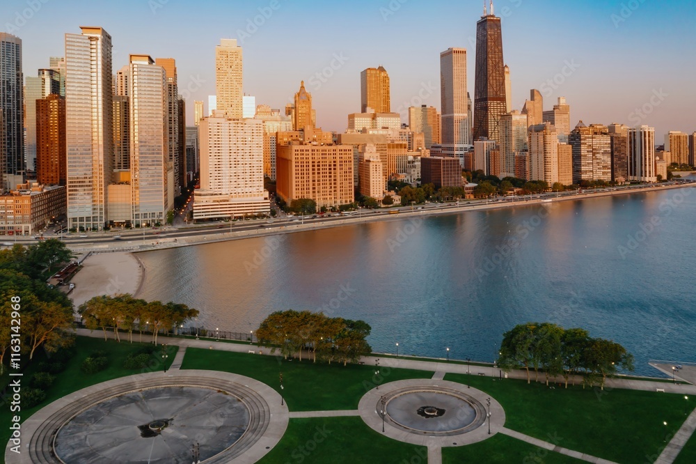Fototapeta premium Chicago skyline at dawn, reflecting on Lake Michigan. Park and fountain in foreground. Beautiful city view. Milton Lee Olive Park, Chicago, Illinois, United States Of America