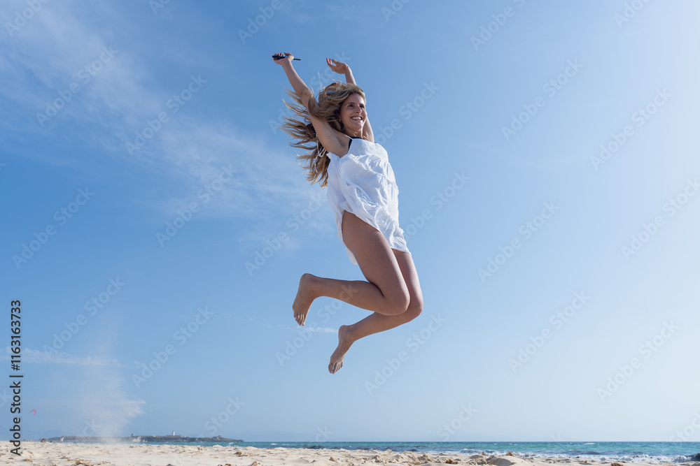 Mujer joven saltando de emoción porque esta feliz y divertida, con un sensacional día de vacaciones en verano en la playa, soleado con cielo azul. Mujer joven saltando de emoción porque esta feliz y divertida, con un sensacional día de vacaciones en verano en la playa, soleado con cielo azul.