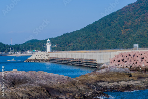 White lighthouse on end of concrete pier in Wando, South Korea.