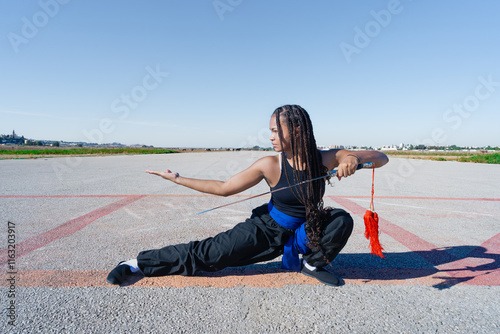 Chica joven luchadora de artes marciales en el paisaje infinito y minimalista de una pista de aterrizaje un día soleado de verano con cielo azul.