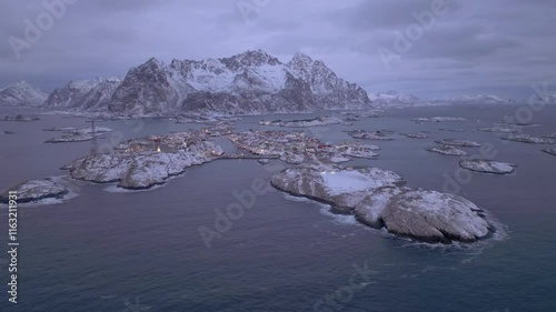 Snow-covered islands in Lofoten, Norway with rugged mountains and a small fishing village visible photo