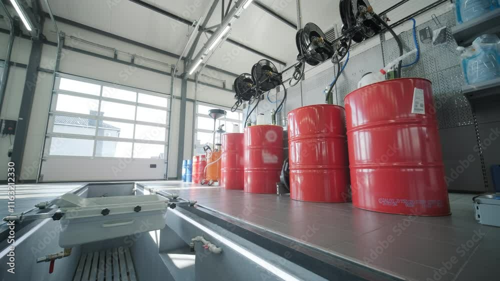 Red oil barrels neatly arranged in a modern auto service workshop. Industrial setting with organized equipment, highlighting professional automotive maintenance and storage solutions