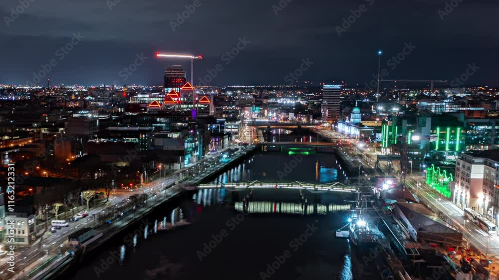 Aerial hyperlapse pullback over the Liffey River at night, unveiling Dublin's vibrant cityscape illuminated by colorful lights