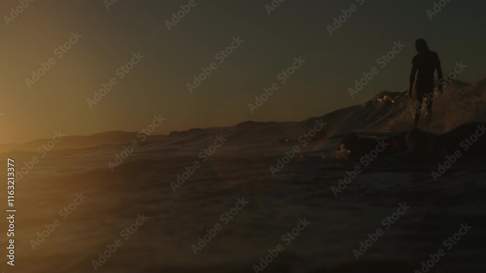 Water spills down as surfer paddles out to lineup and tracking follows person gliding to sunset Water spills down as surfer paddles out to lineup and tracking follows person gliding to sunset