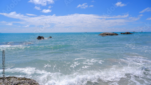 Fototapeta Naklejka Na Ścianę i Meble -  Natural scenery A beautiful tropical beach with soft white sand and clear turquoise water. Lush green trees line the beach and gentle waves crash against the shore.