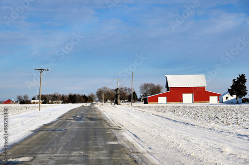 A red barn sits next to a field dusted with snow along a lonely contry road on the first day of winter in northern Illinois.  photo