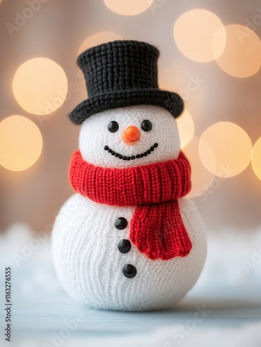A cheerful snowman made of knitted fabric, adorned with a black top hat and an orange scarf, set against a soft, blurred background of warm lights.